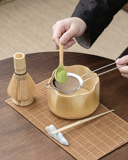 Preparing matcha with a bamboo bowl, scoop, and whisk on a bamboo placemat